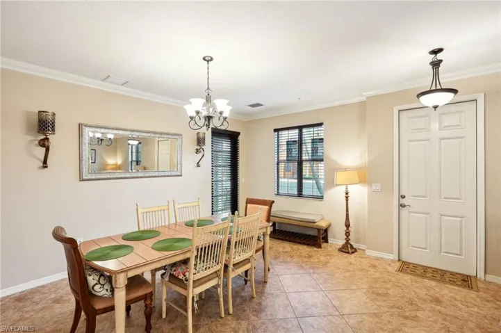 Dining room with light tile patterned flooring, crown molding, and a chandelier