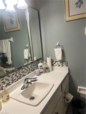 Bathroom vanity featuring a rectangular integrated sink, chrome faucet, and mosaic tile backsplash