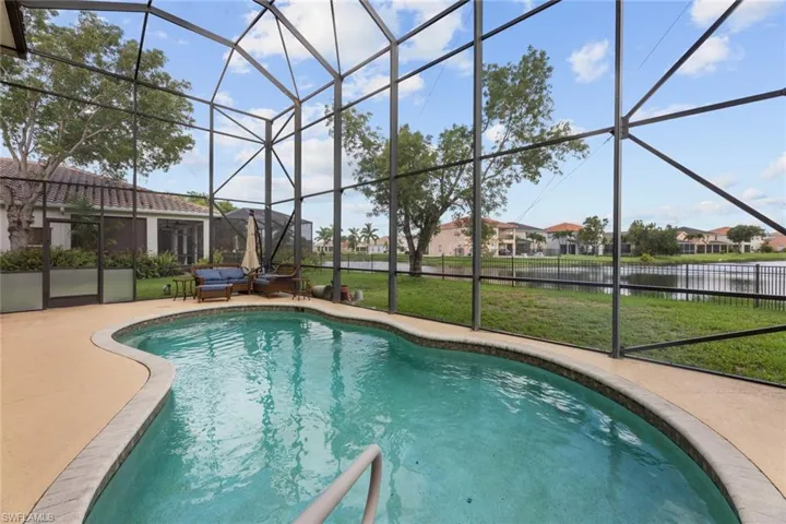 View of pool featuring a patio area, glass enclosure, and a lawn
