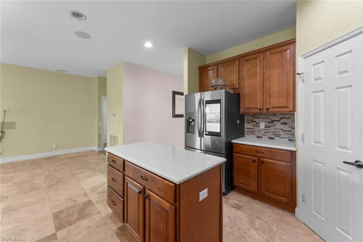 Kitchen featuring a center island, stainless steel fridge, tasteful backsplash, and light tile floors
