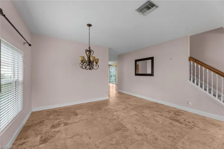 Unfurnished dining area featuring plenty of natural light, light tile floors, and an inviting chandelier