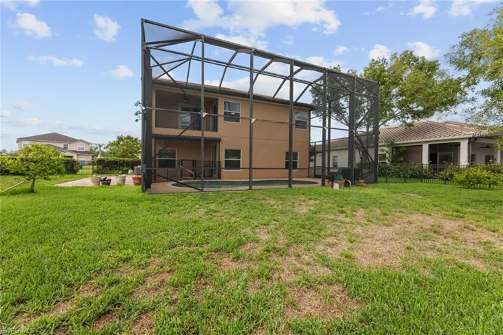 Rear view of house featuring a lanai and a lawn