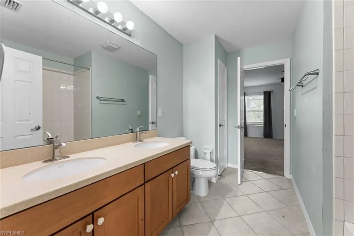 Bathroom with dual vanity, toilet, and tile floors