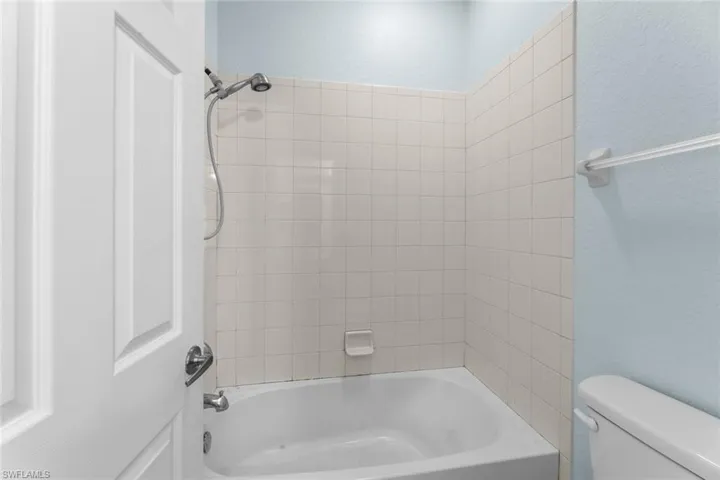 Bathroom featuring tiled shower / bath combo and toilet