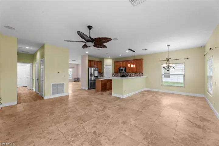 Unfurnished living room with light tile floors and ceiling fan with notable chandelier
