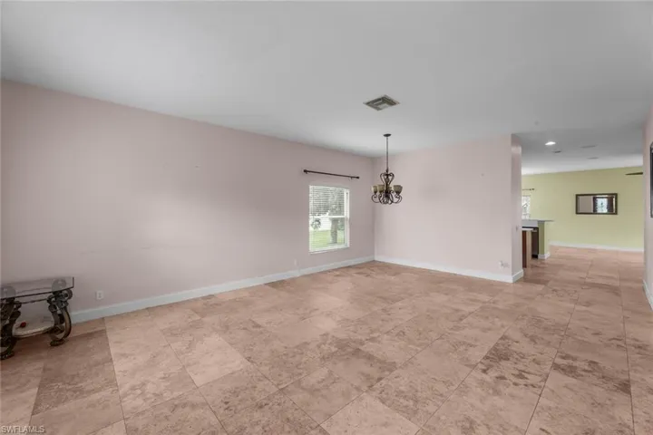 Tiled spare room with a notable chandelier
