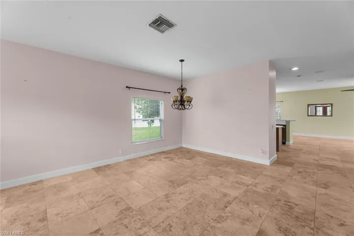 Empty room featuring a notable chandelier and light tile floors