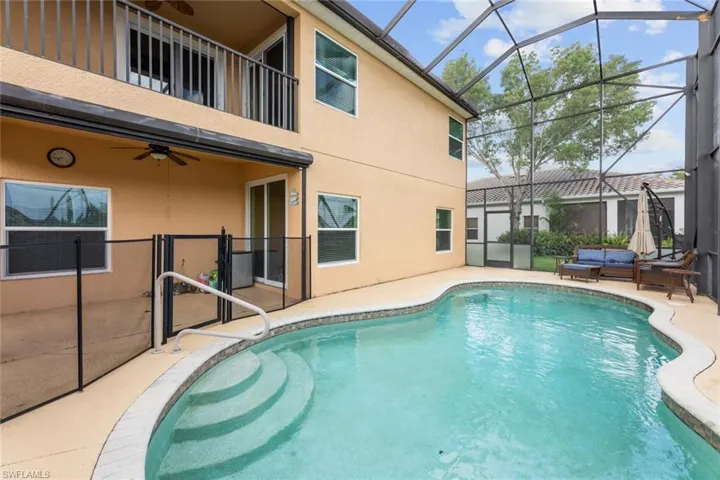 View of swimming pool with glass enclosure, a patio area, and ceiling fan