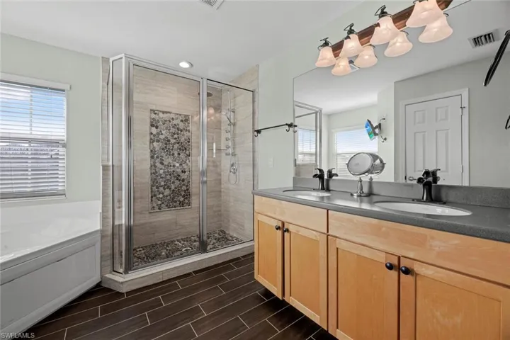Bathroom featuring tile flooring, oversized vanity, separate shower and tub, and double sink