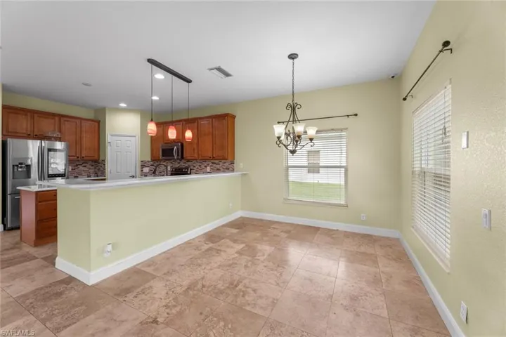 Kitchen featuring stainless steel appliances, kitchen peninsula, backsplash, and light tile floors