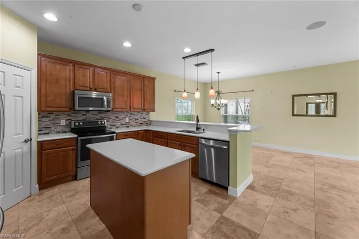 Kitchen with a kitchen island, appliances with stainless steel finishes, backsplash, pendant lighting, and sink