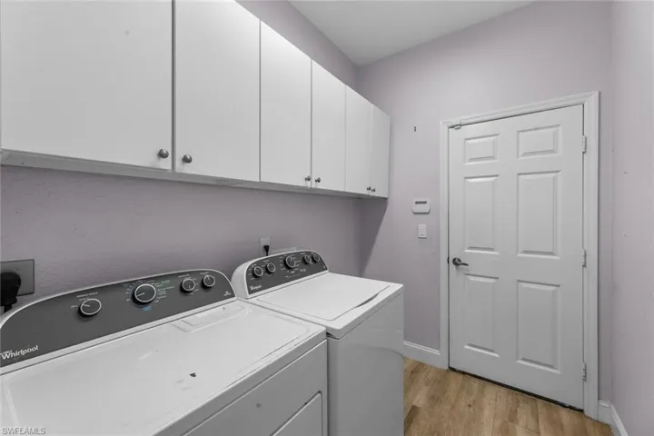 Washroom featuring washing machine and dryer, light hardwood / wood-style flooring, hookup for an electric dryer, and cabinets