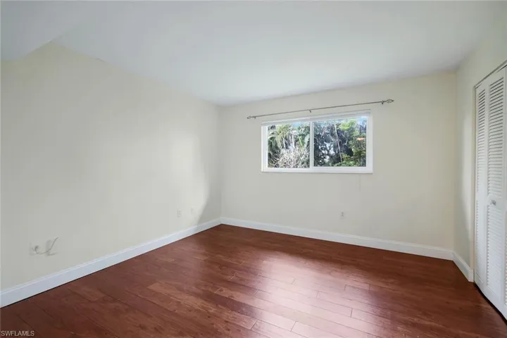 Unfurnished bedroom featuring dark wood-style floors and a closet