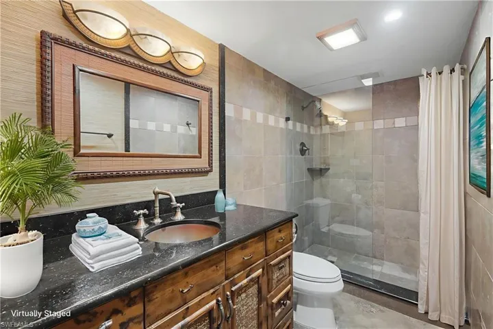 Full bathroom featuring vanity, a walk in shower, and tile walls