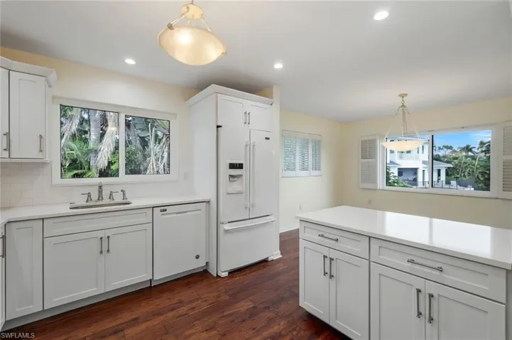 Kitchen with decorative light fixtures, white appliances, white cabinets, dark wood-style floors, and recessed lighting