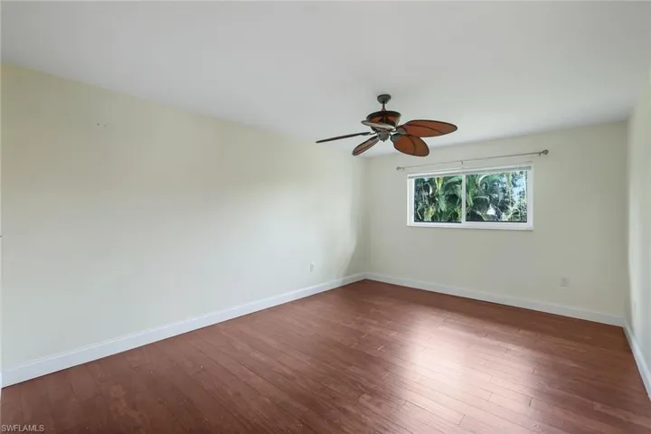 Unfurnished room with dark wood-style floors and ceiling fan