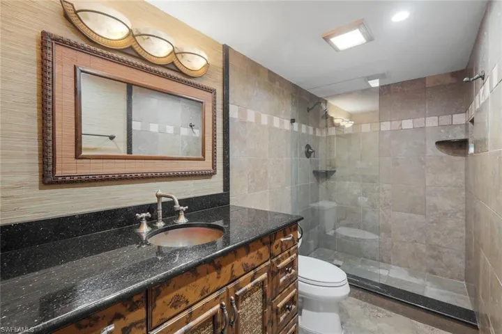 Full bath with vanity, walk in shower, tile walls, and recessed lighting