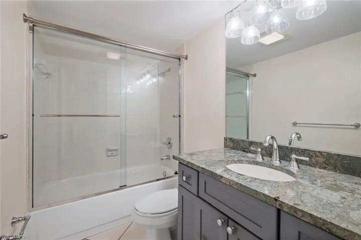 Full bathroom with vanity, combined bath / shower with glass door, and light tile patterned floors
