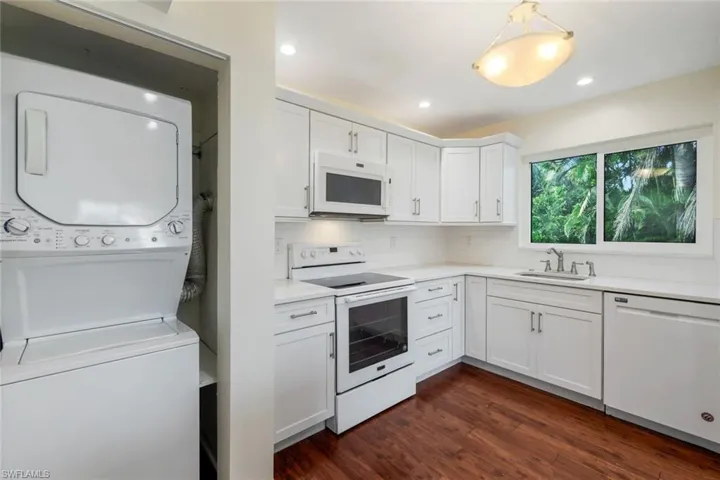 Kitchen with white appliances, dark wood-style floors, white cabinetry, tasteful backsplash, and recessed lighting
