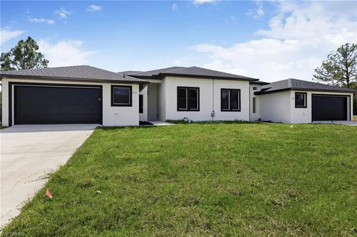 Prairie-style house featuring an attached garage, a front yard, driveway, and stucco siding