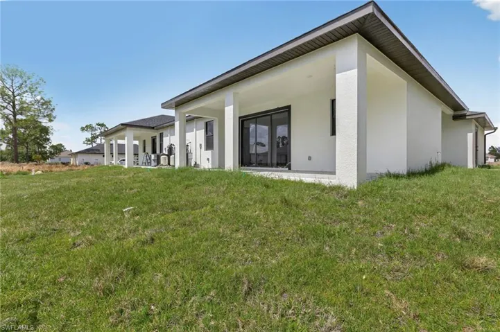 Back of house with a yard, stucco siding, and a patio
