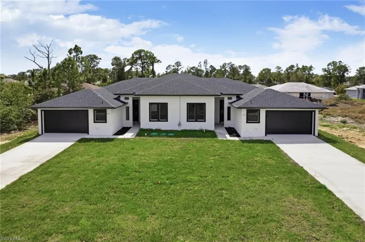 Prairie-style home featuring an attached garage, roof with shingles, and stucco siding