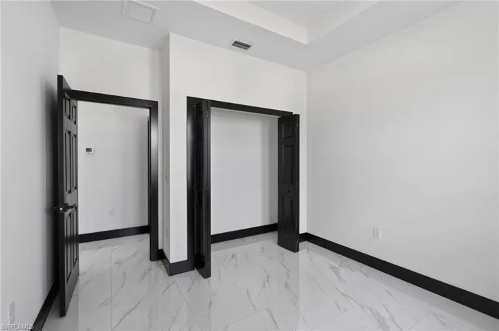 Unfurnished bedroom with light marble finish floors and a closet