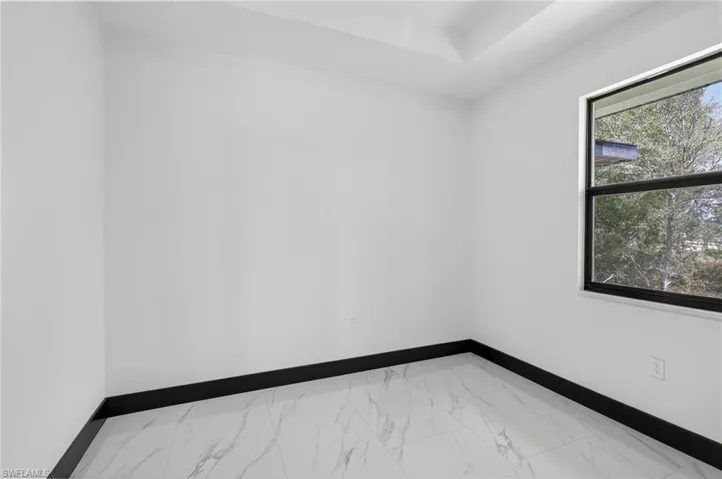 Spare room featuring baseboards and light marble finish flooring