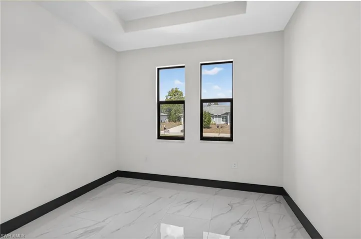 Unfurnished room featuring light marble finish flooring and a raised ceiling