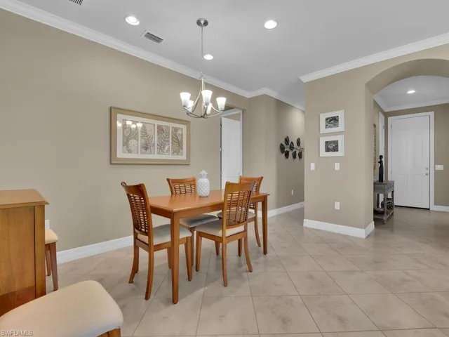 Tiled dining room featuring a notable chandelier and ornamental molding
