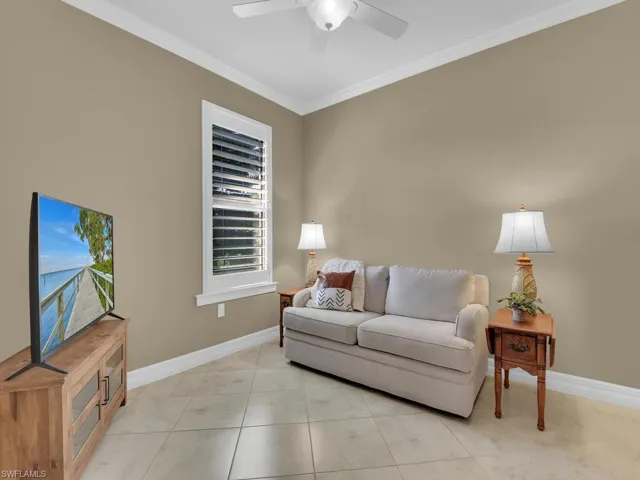 Tiled living room featuring ceiling fan and crown molding