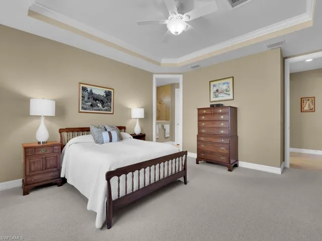 Bedroom with light carpet, ceiling fan, crown molding, and a raised ceiling