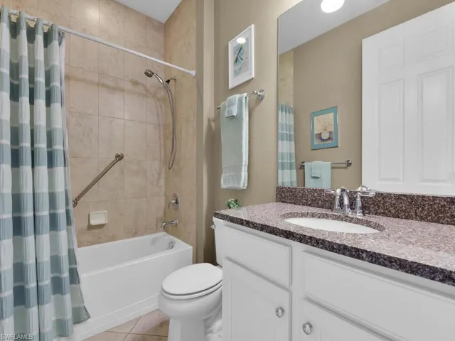 Full bathroom with vanity, shower / bath combo, toilet, and tile patterned floors