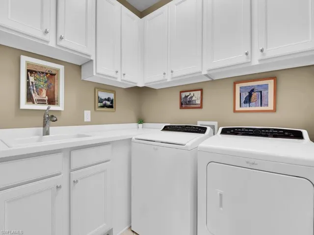 Laundry room featuring sink, washing machine and dryer, and cabinets