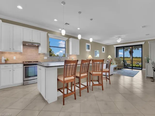 Kitchen with a wealth of natural light, stainless steel range, pendant lighting, and white cabinetry