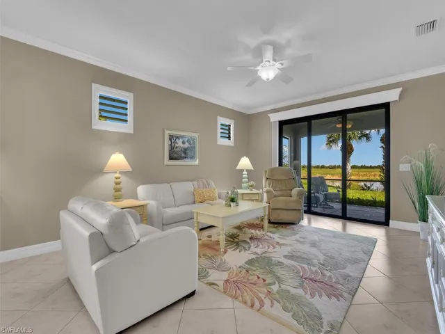 Living room with crown molding, ceiling fan, and light tile patterned floors