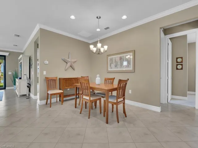 Tiled dining area with ornamental molding and an inviting chandelier