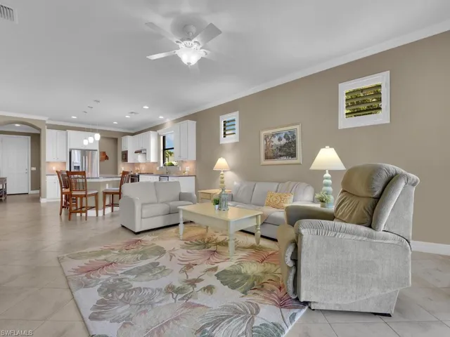 Living room featuring ceiling fan, ornamental molding, and light tile patterned floors