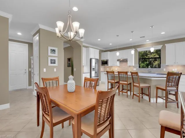 Dining area with sink, crown molding, a notable chandelier, and light tile patterned floors
