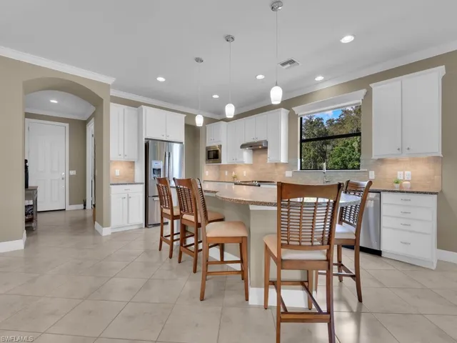 Kitchen with white cabinetry, appliances with stainless steel finishes, pendant lighting, and a kitchen island