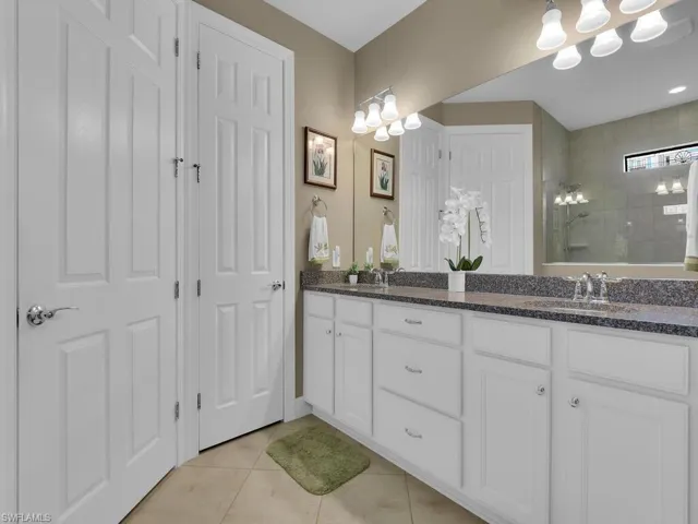 Bathroom with vanity, tiled shower, and tile patterned flooring