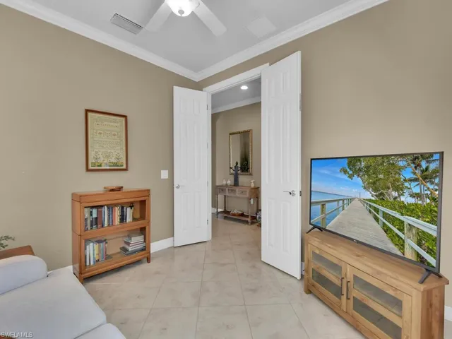 Tiled living room with ornamental molding and ceiling fan