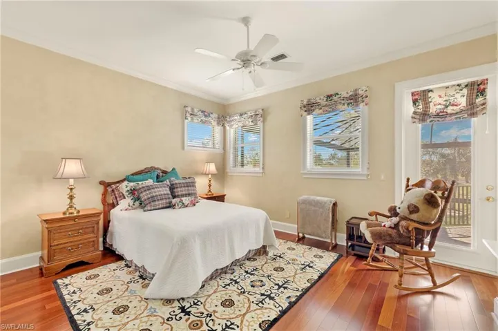 Bedroom with hardwood / wood-style floors, access to exterior, visible vents, and ornamental molding
