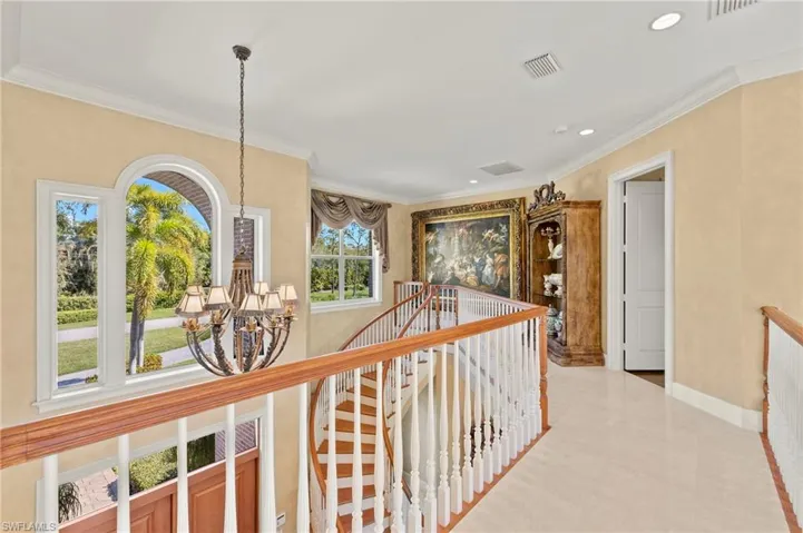 Corridor with an inviting chandelier, an upstairs landing, visible vents, and ornamental molding