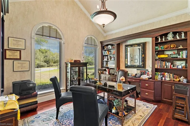 Office space featuring high vaulted ceiling, crown molding, and dark wood-style flooring