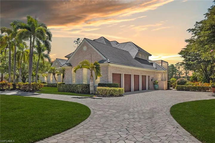 View of front of property with a front yard, decorative driveway, brick siding, and an attached garage