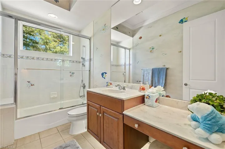 Full bathroom featuring tile patterned flooring, toilet, vanity, and shower / bath combination with glass door