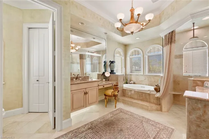 Bathroom with vanity, ornamental molding, a walk in shower, a garden tub, and a chandelier