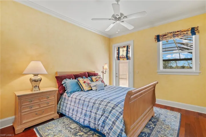 Bedroom with ornamental molding, a ceiling fan, dark wood finished floors, baseboards, and access to exterior