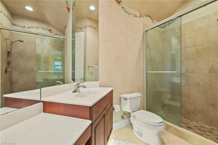 Bathroom featuring tile patterned flooring, a shower stall, toilet, and vanity